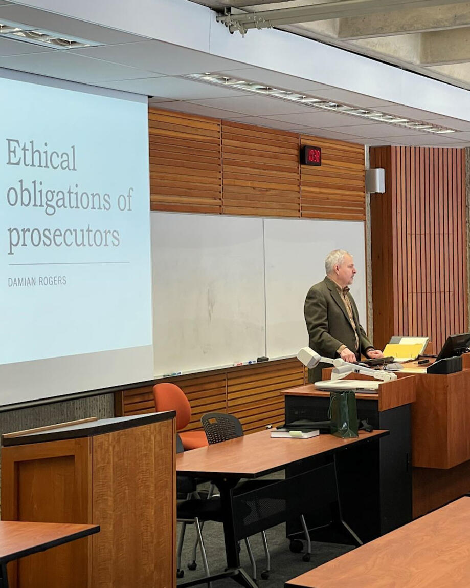 A picture of Damian Rogers at a podium presenting to a University of Alberta Faculty of Law legal ethics class.